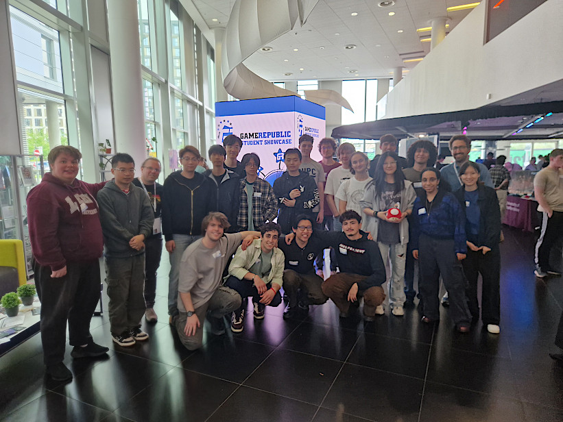 Group picture with the students and lecturers at the Games Republic Student Showcase. The event space is in the background.